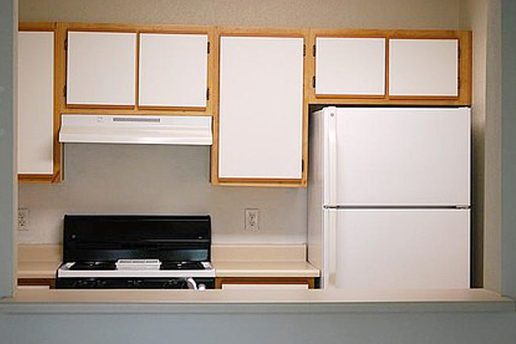 Kitchen, white refrigerator, black stove, white cabnet doors with brown outer paneling