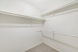 Interior Unit Walk in Closet, neutral toned carpeting, multiple shelves.