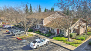 Exterior Aerial of single residential building, parking in front, trees and meticulously groomed landscaping leading to and around the building, 2 story walk up.