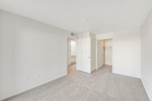 Interior Unit Bedroom, Neutral toned carpeting, wood-like floors in hallway, walk-in closet.