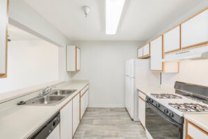 Interior Unit Kitchen, White cabinetry, laminate countertops, wood-like flooring, double stainless sink, breakfast bar joined to kitchen, gas stove