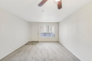 Interior Unit Living room, neutral toned carpeting, overhead lights/fan window to the right of entrance door.